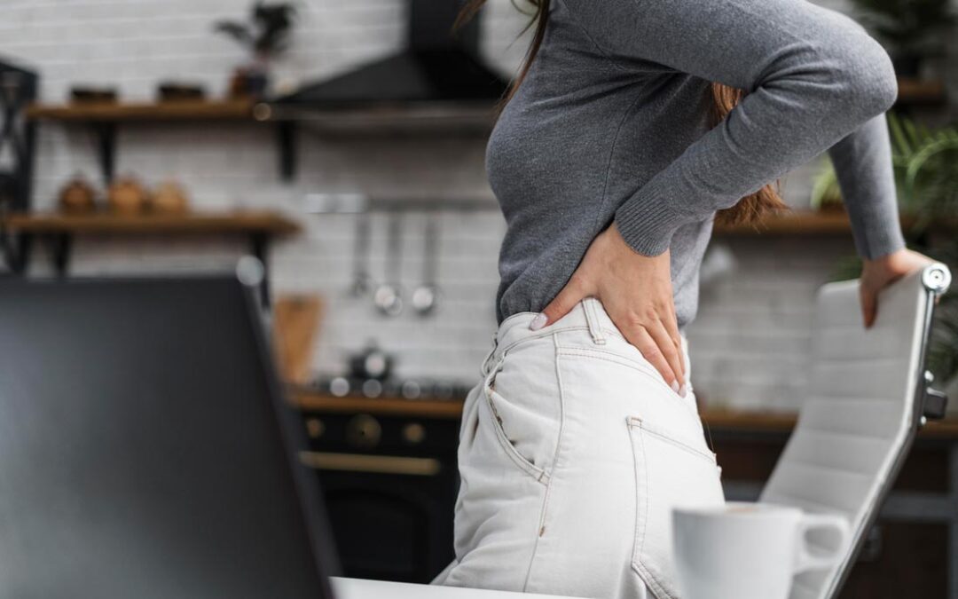 Una mujer doliéndose de la cintura en una cocina.